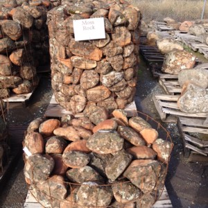 Photo of Moss Rock. A round redish colored rock with lichen and moss in two sizes head and double head. Use for Drystack stone wall, and Masonry Stone Wall. Natural stone sold by Rolleri Landscape Products.